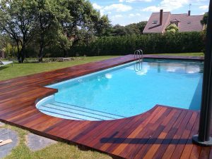 Tarima de madera de ipe en jardin con piscina