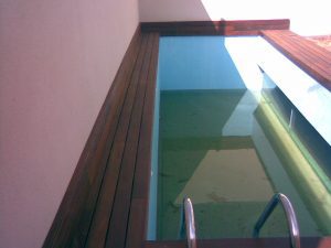 Coronacion de piscina con tarima de madera exotica de ipe con tragaluz de cristal